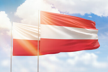 Sunny blue sky and flags of austria and poland