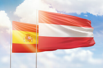 Sunny blue sky and flags of austria and spain
