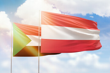 Sunny blue sky and flags of austria and sudan
