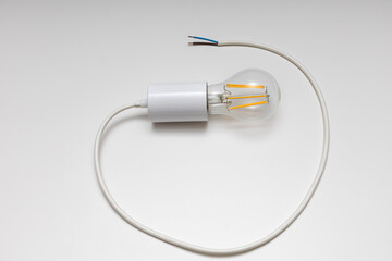 an electric lamp screwed into a socket with a cable lies on a white