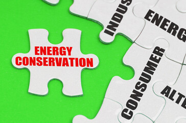 On a green surface are white puzzles with text, on a separate puzzle there is an inscription - Energy Conservation