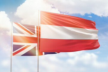 Sunny blue sky and flags of austria and united kingdom