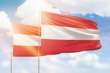 Sunny blue sky and flags of austria and austria
