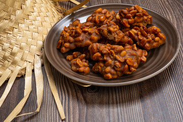 .Peanut candy served in a brown silver with straw hat on wooden background