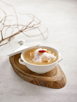 Grouper Fillet in Winter Melon and Conpoy Soup Served in a bowl isolated on wooden board side view on grey background