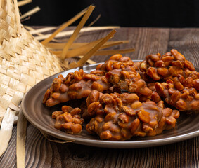 .Peanut candy served in a brown silver with straw hat on wooden background