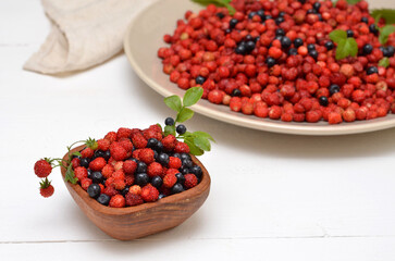 still life with wild berries on the table, strawberries and blueberries in a bowl