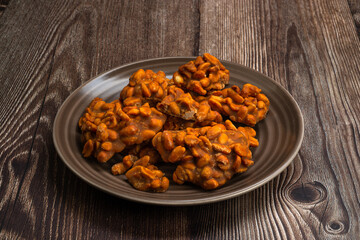 Peanut candy served in a brown silver on wooden background.