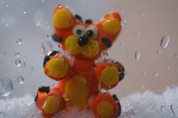 The figure of a small tiger cub on the background of a wet window.