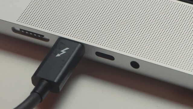 Close-up of charging wire inserted into laptop. Action. Charging your phone via laptop. Phone charging cable is connected to laptop input
