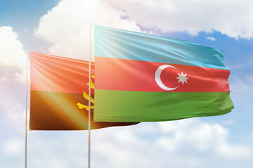 Sunny blue sky and flags of azerbaijan and angola