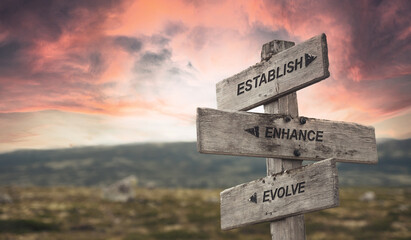 establish enhance evolve text quote caption on wooden signpost outdoors in nature with dramatic sunset skies. Panorama crop. ESG Concept