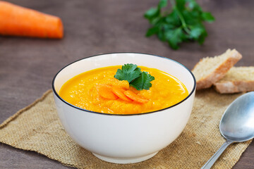 bowl of carrot soup with vegetables.homemade orange carrot soup with green parsley in a bowl on...