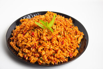 auger pasta on black plate on white background