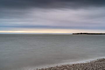 Sea pebble beach with boulders and long gangway in the water. L'houmeau beach, France