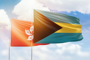 Sunny blue sky and flags of bahamas and hong kong
