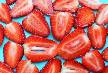 Ripe juicy strawberries cut into thin slices. Background from strawberries. Red berries on a blue plate