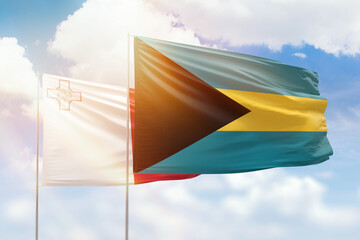 Sunny blue sky and flags of bahamas and malta