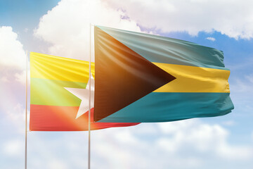Sunny blue sky and flags of bahamas and myanmar