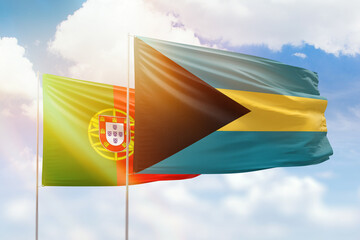 Sunny blue sky and flags of bahamas and portugal