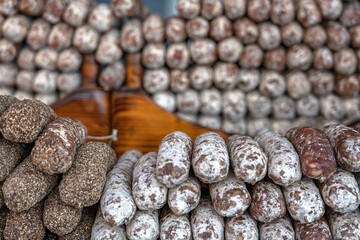 Stacks of dry-cured sausages - saucisson, typically made of pork, or a mixture of pork and other meats. Some variation contains spices and herbs, mushrooms, dried fruits, nuts, or cheese.