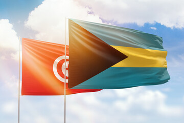 Sunny blue sky and flags of bahamas and tunisia