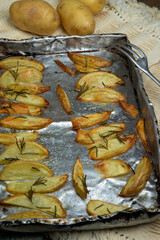 Portion of roasted potato, seasoned with rosemary, in aluminum baking tray