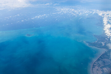 Aerial view of blue ocean and coast land with a few clouds