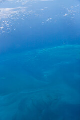 Aerial view of blue ocean and underwater landmarks with a few clouds