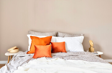 White and red pillows on a comfortable double bed in cozy interior of bedroom. Bedding and blanket in stylish design in modern room in hotel. New apartment. Copy space od the empty wall.