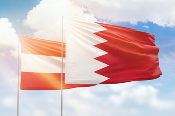 Sunny blue sky and flags of bahrain and austria