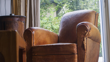 Canapé en cuir dans un salon.
Salon en bois avec un vieux fauteuil brun.
pièce de cuir abimé  - obrazy, fototapety, plakaty