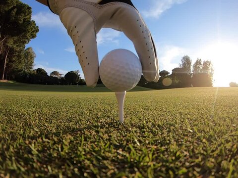 Golfer placing golf ball on the tee at golf course before shot