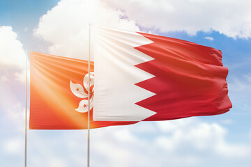 Sunny blue sky and flags of bahrain and hong kong