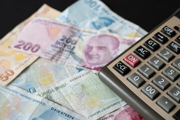 Turkish Liras and calculator on black background.