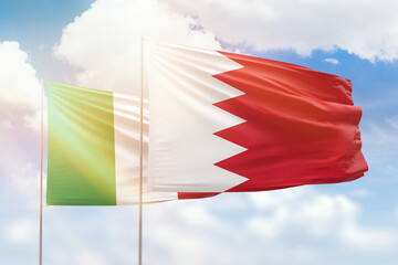 Sunny blue sky and flags of bahrain and italy