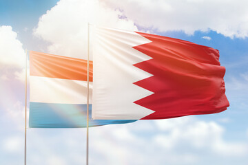 Sunny blue sky and flags of bahrain and luxembourg