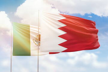 Sunny blue sky and flags of bahrain and mexico