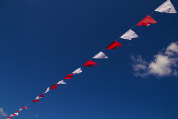 Bandeirolas penduradas por fio com céu azul ao fundo.