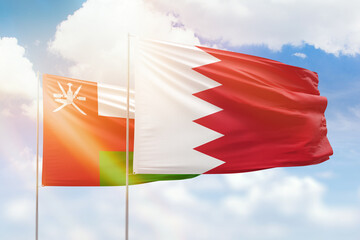 Sunny blue sky and flags of bahrain and oman