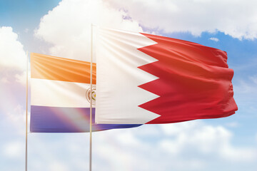 Sunny blue sky and flags of bahrain and paraguay
