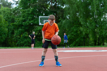 Obraz premium Boy playing basketball on a park court. Concept of a sports lifestyle, training, camp, leisure, vacation. Horizontal sport theme poster, greeting cards, headers, website and app