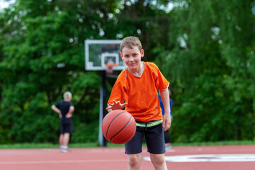 Boy playing basketball on a park court. Concept of a sports lifestyle, training, camp, leisure, vacation. Horizontal sport theme poster, greeting cards, headers, website and app