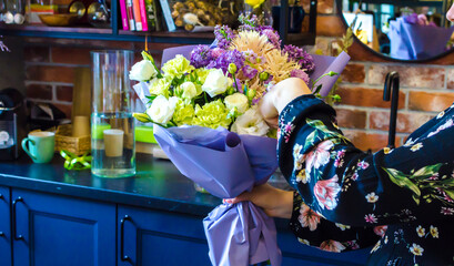 florist collects a bouquet of flowers in a purple package
