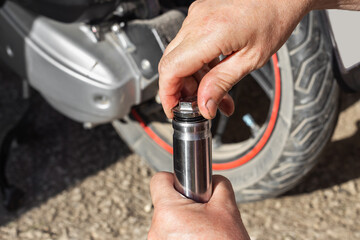 Oil change, motorcycle maintenance and repair. A car mechanic unscrews the plug on the shock...