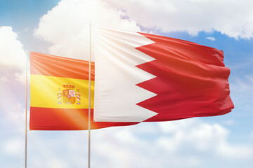 Sunny blue sky and flags of bahrain and spain