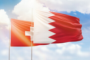 Sunny blue sky and flags of bahrain and switzerland