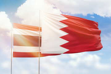 Sunny blue sky and flags of bahrain and thailand
