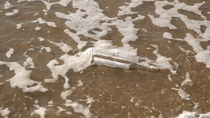 A message in a bottle washed up on the beach by waves
