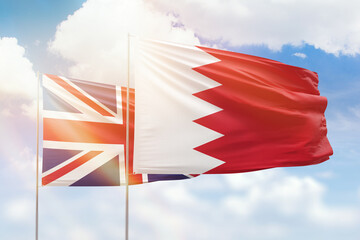 Sunny blue sky and flags of bahrain and united kingdom